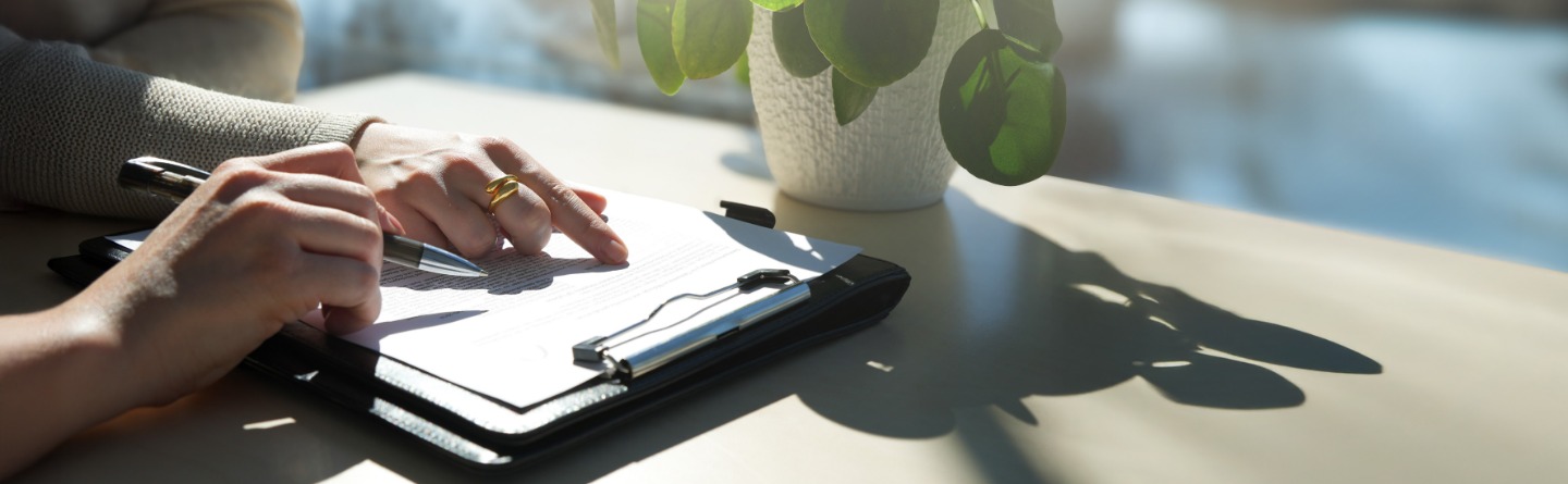 Person schreibt Notizen auf einem Klemmbrett  Eine Person, die mit einem Stift auf einem Klemmbrett schreibt.