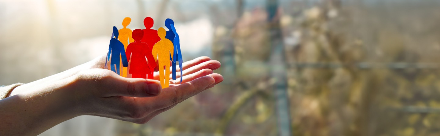 Offen ausgestreckte Hände mit bunten Menschensilhouetten 2 Hände sind nach oben offen ausgestreckt. Darauf ist ein Kreis mit menschlichen, bunten Umrissen.