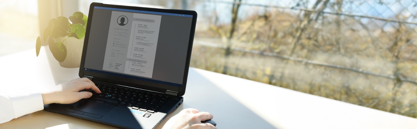 Eine Person arbeitet an einem Laptop. Dort sieht man einen Lebenslauf, der gerade bearbeitet wird.