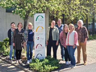 8 Personen stehen vor einem Aufsteller mit IFD-Logo