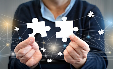 Eine Person hält zwei weiße, sich ergänzende Puzzleteile. Im Hintergrund wird ein Netzwerk gebildet.