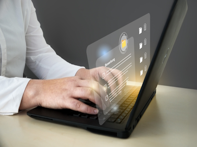 Person mit Laptop und transparenter Benutzeroberfläche Person arbeitet am Laptop. Die Hände sind auf der Tastatur. Man sieht eine virtuelle Oberfläche.