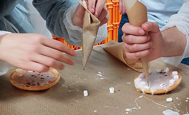 Teilnehmerinnen und Teilnehmer verzieren Gebäck