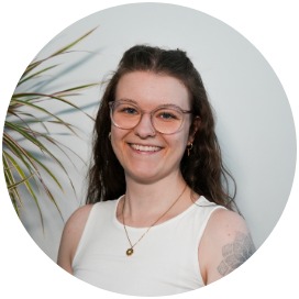 Annette Fick Das Bild zeigt eine Frau die neben einer Blume steht.